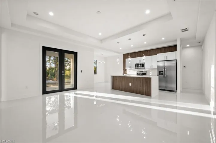 Kitchen featuring stainless steel appliances, pendant lighting, french doors, a kitchen island, and a tray ceiling