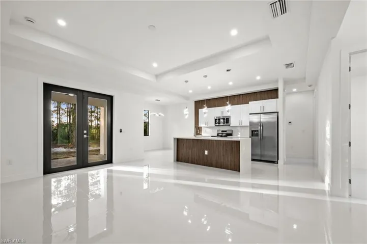 Kitchen with stainless steel appliances, a raised ceiling, french doors, hanging light fixtures, and open floor plan