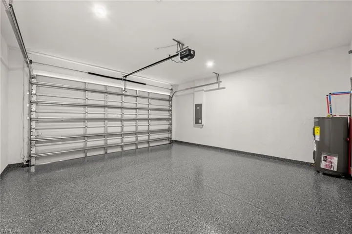 Garage featuring water heater, a garage door opener, and electric panel