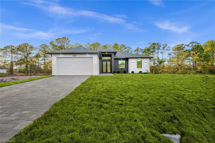 Prairie-style home with stucco siding, decorative driveway, a garage, a front yard, and roof with shingles