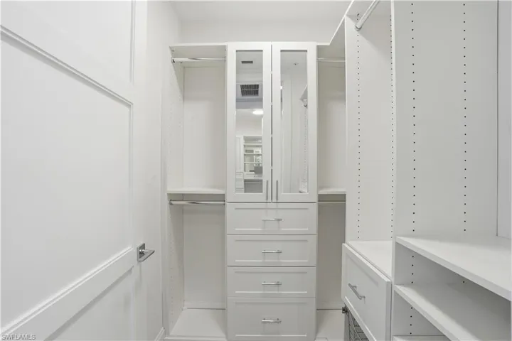 His and her closets with built in shelves and cabinetry.
