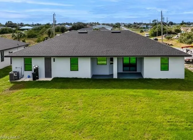 Back of property featuring stucco siding, roof with shingles, a patio, and a yard