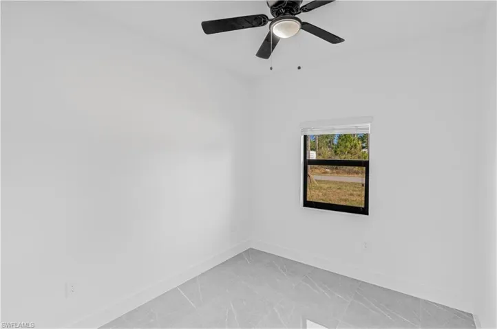 Spare room featuring light marble finish floors and a ceiling fan