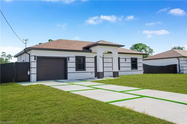 View of front of home with an attached garage, driveway, stucco siding, and roof with shingles