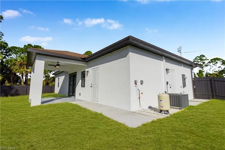 Rear view of property featuring ceiling fan, stucco siding, and a patio area