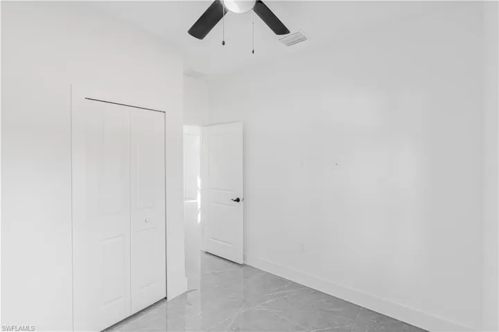 Unfurnished bedroom featuring a closet, light marble finish flooring, and a ceiling fan