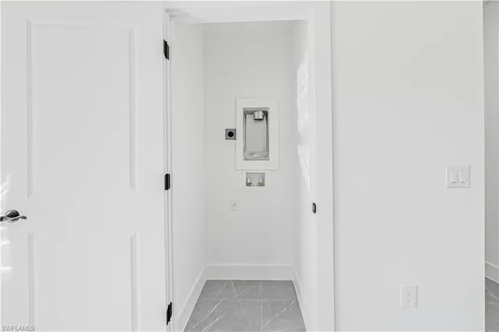 Laundry area with washer hookup and light marble finish floors