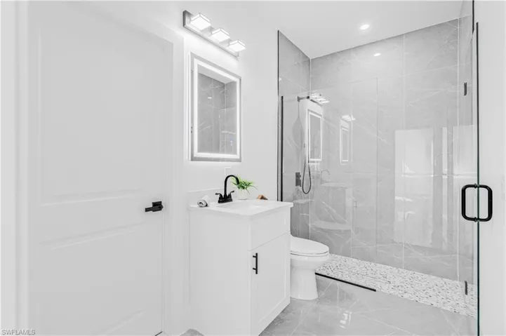 Bathroom with a marble finish shower, vanity, recessed lighting, and light marble finish floors