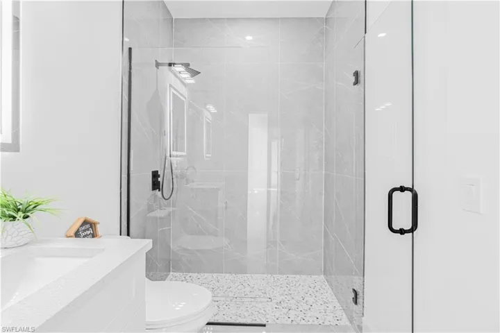 Bathroom featuring vanity and a marble finish shower