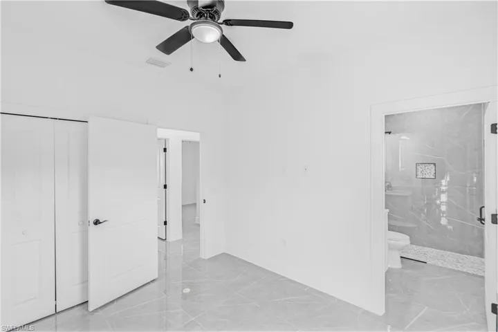 Unfurnished bedroom with ceiling fan, light marble finish floors, and a closet