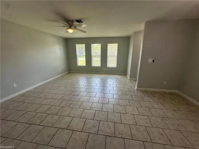 Empty room featuring a ceiling fan and light tile patterned floors