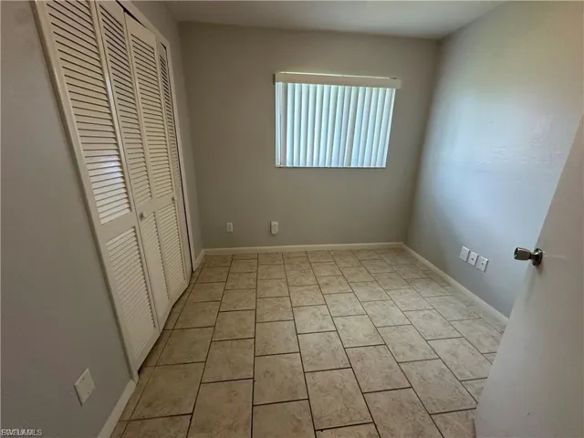 Unfurnished bedroom with a closet and light tile patterned flooring