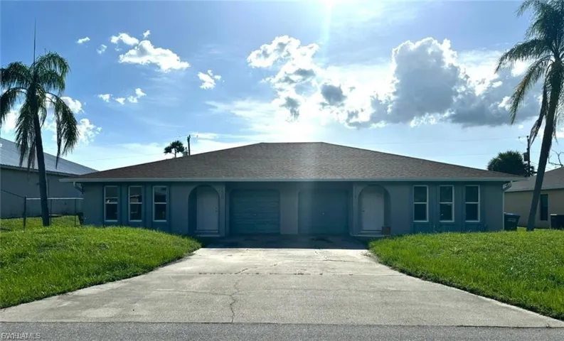 Single story home with stucco siding, a front yard, and driveway