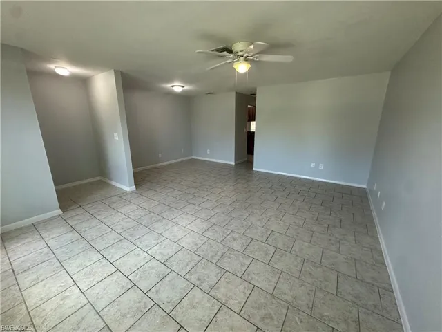 Empty room with ceiling fan and light tile patterned floors