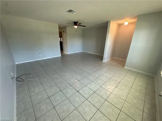 Empty room with light tile patterned flooring and a ceiling fan