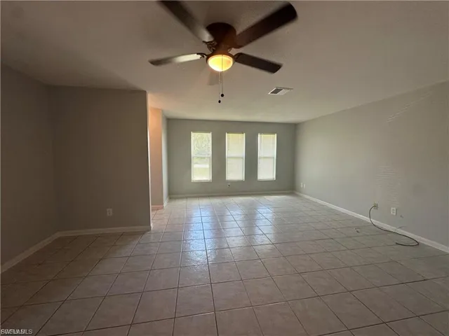 Unfurnished room with light tile patterned floors and ceiling fan