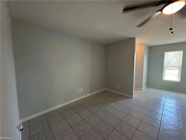 Empty room with ceiling fan and light tile patterned flooring