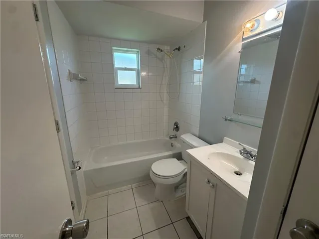 Bathroom with vanity, shower / bathtub combination, and light tile patterned flooring