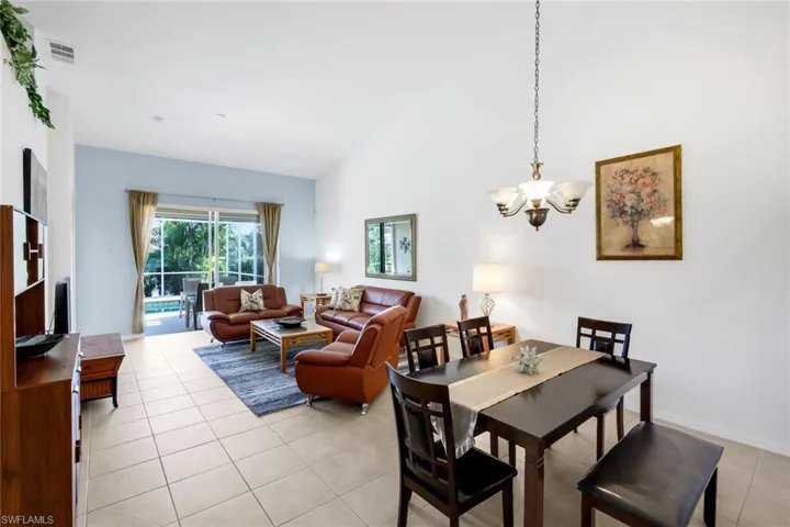 Dining area featuring light tile patterned floors, high vaulted ceiling, and a chandelier