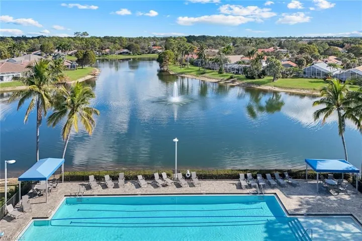 Community pool with a patio, view of scattered trees, and a water view