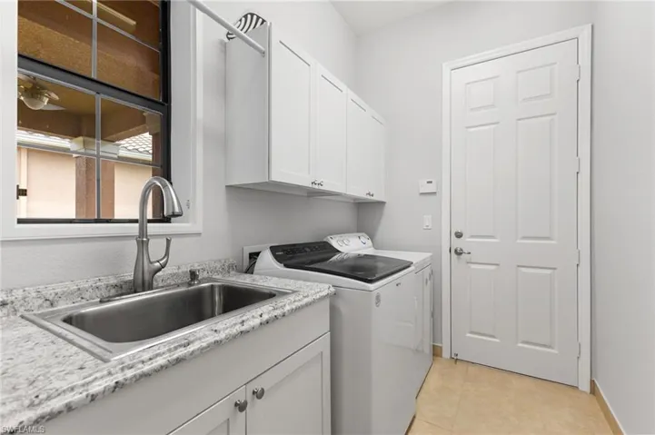 Washroom featuring sink, separate washer and dryer, cabinets, and light tile patterned floors