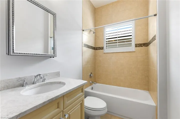 Full bathroom featuring vanity, tiled shower / bath combo, and toilet