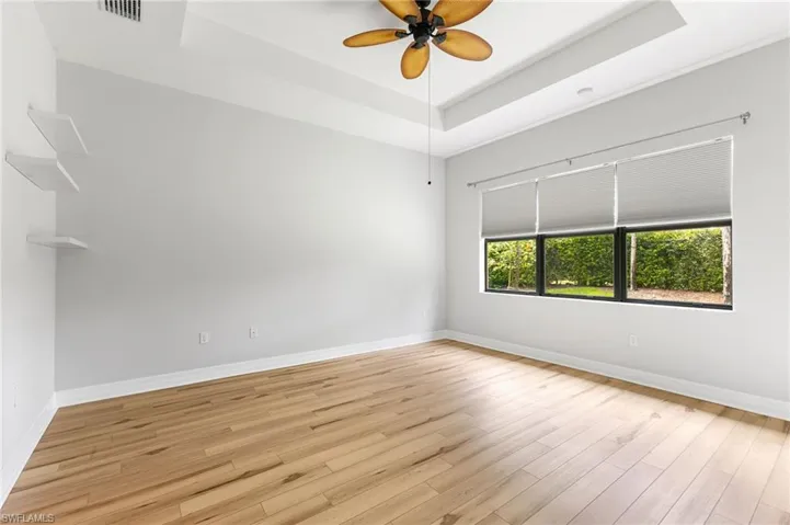 Unfurnished room with ceiling fan, a raised ceiling, and light hardwood / wood-style floors