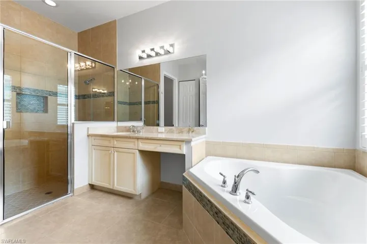 Bathroom featuring tile patterned floors, vanity, and separate shower and tub