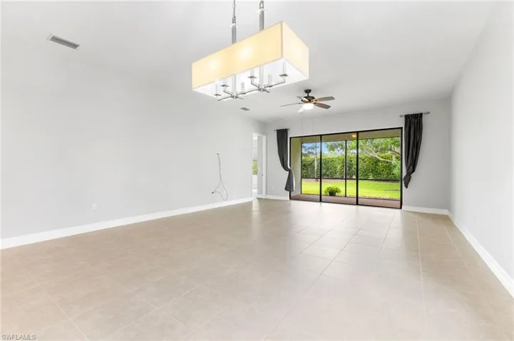 Unfurnished room with ceiling fan with notable chandelier and light tile patterned floors