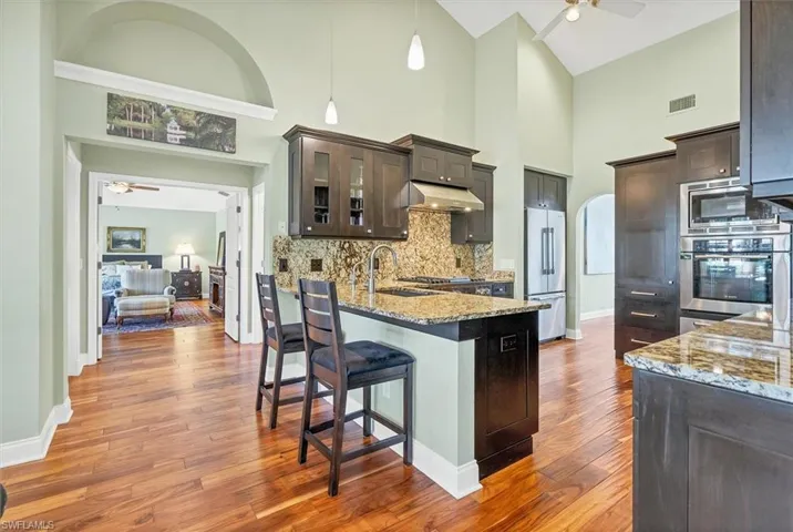 Kitchen with sink, high vaulted ceiling, appliances with stainless steel finishes, dark hardwood / wood-style flooring, and ceiling fan