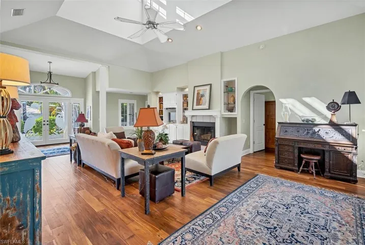 Living room with ceiling fan, dark hardwood / wood-style floors, high vaulted ceiling, and a tile fireplace