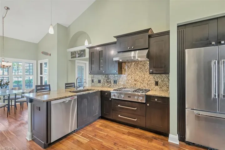 Kitchen featuring light hardwood / wood-style floors, sink, stainless steel appliances, and high vaulted ceiling
