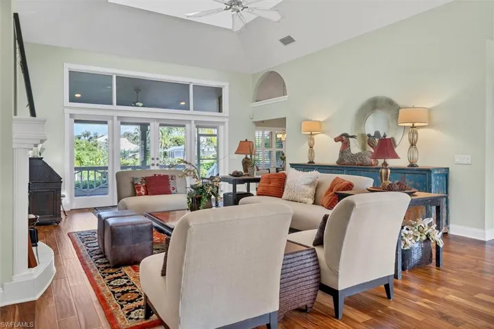 Living room with high vaulted ceiling, ceiling fan, and hardwood / wood-style flooring