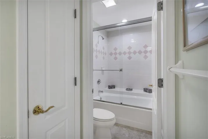Bathroom featuring enclosed tub / shower combo, toilet, and tile patterned floors