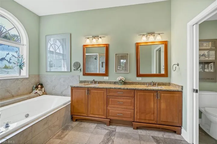 Full bathroom featuring shower with separate bathtub, vanity, and toilet