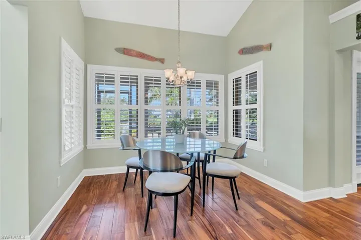 Dining area featuring wood-type flooring, high vaulted ceiling, and a notable chandelier
