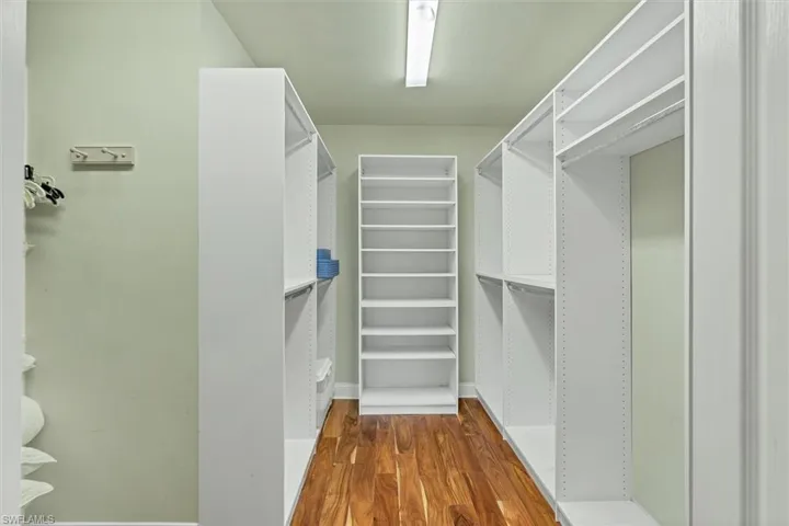 Walk in closet with dark wood-type flooring