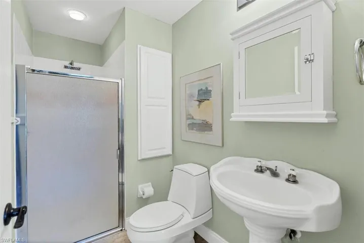 Great Pool Bathroom featuring sink, a shower with shower door, and toilet