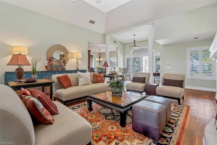 Living room with an inviting chandelier, wood-type flooring, high vaulted ceiling, and french doors