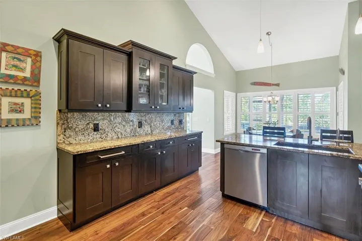 Kitchen featuring pendant lighting, sink, high vaulted ceiling, dark hardwood / wood-style flooring, and stainless steel dishwasher