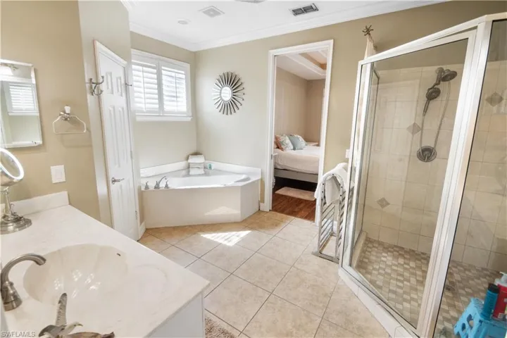 Bathroom with vanity, tile floors, crown molding, and plus walk in shower