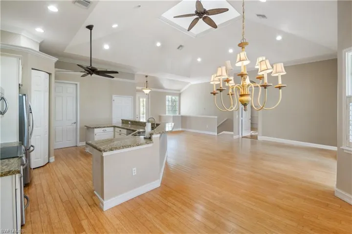 Kitchen featuring sink, light hardwood / wood-style floors, ceiling fan with notable chandelier, and pendant lighting