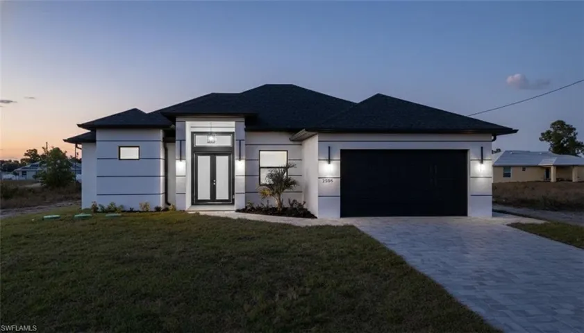 View of front of house with a front yard, stucco siding, decorative driveway, and a garage