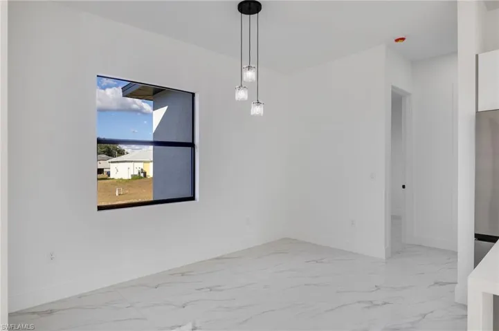 Unfurnished dining area featuring light marble finish flooring and baseboards