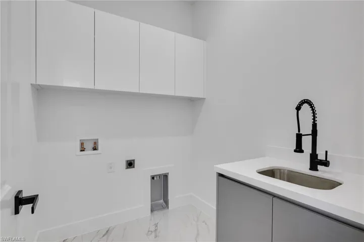 Laundry room featuring electric dryer hookup, light marble finish floors, cabinet space, and hookup for a washing machine