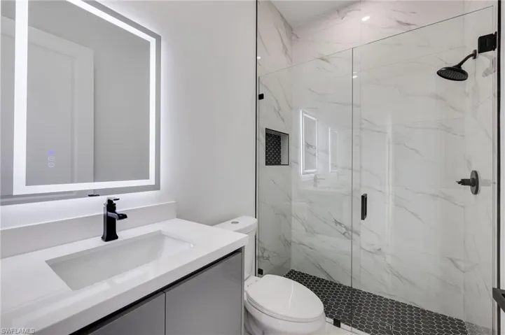 Bathroom featuring vanity and a marble finish shower