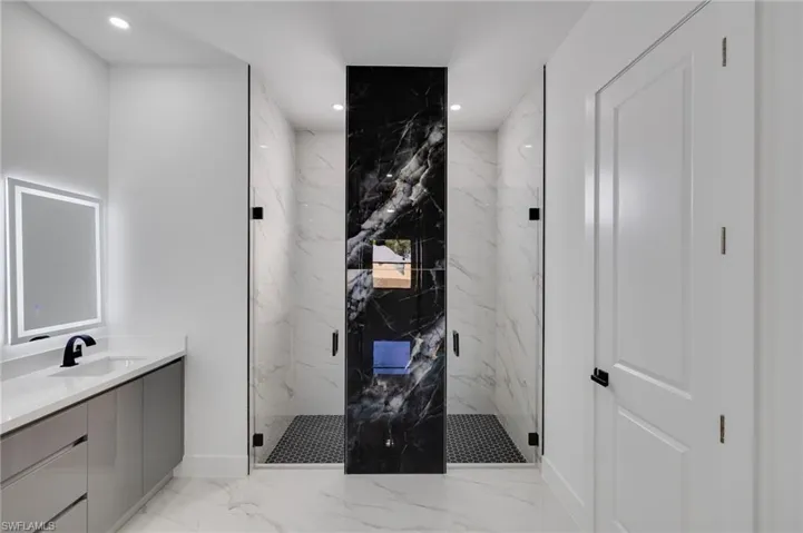 Bathroom with light marble finish flooring, a marble finish shower, recessed lighting, and vanity