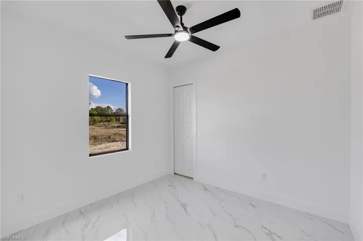 Unfurnished room with light marble finish floors and a ceiling fan
