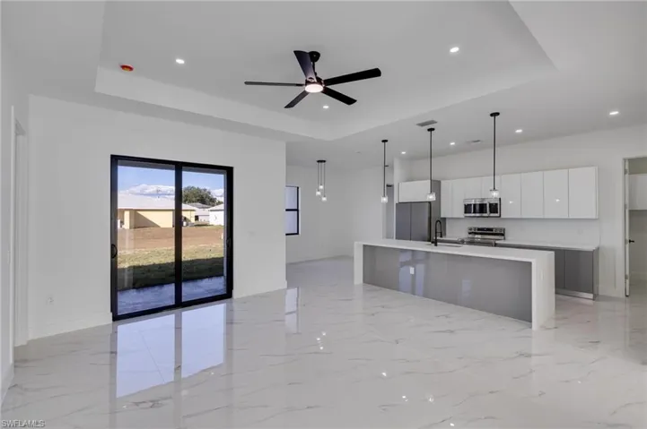 Kitchen with white cabinetry, a kitchen island with sink, open floor plan, modern cabinets, and a raised ceiling