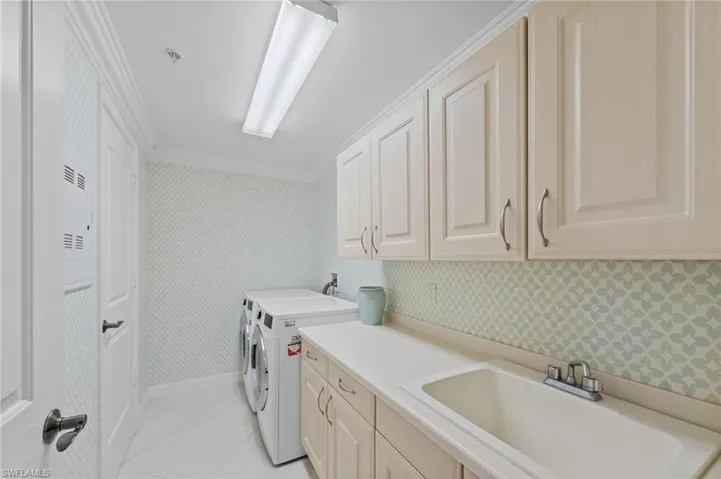 The laundry room features a utility sink, upper and lower cabinetry, and a countertop